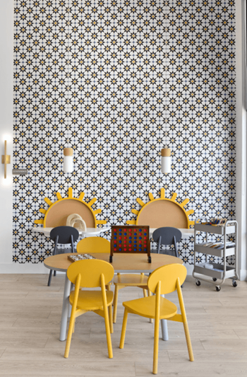 A dining room with a table and yellow chairs and a wall covered in tiles